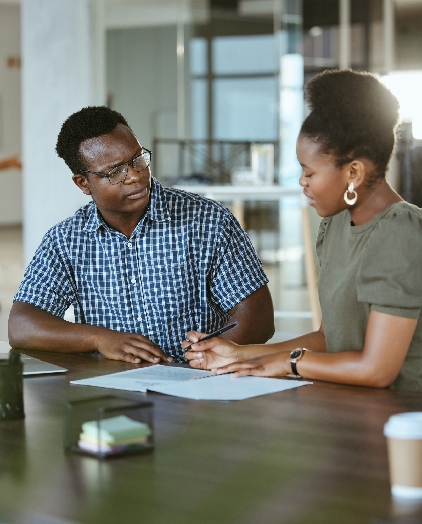 Two african american businesspeople having a meeting and looking at a report together at work. Busi